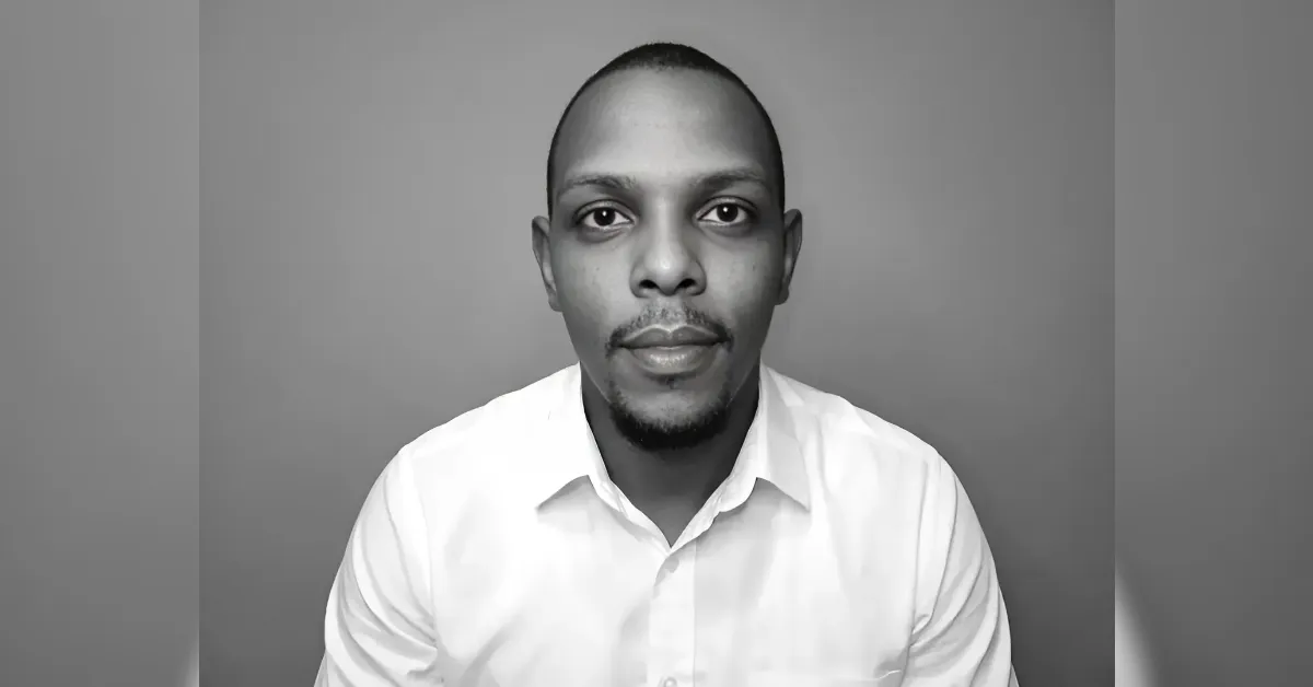 Head-and-shoulders black-and-white portrait of a man in a white shirt, looking straight at the camera (profile photo).