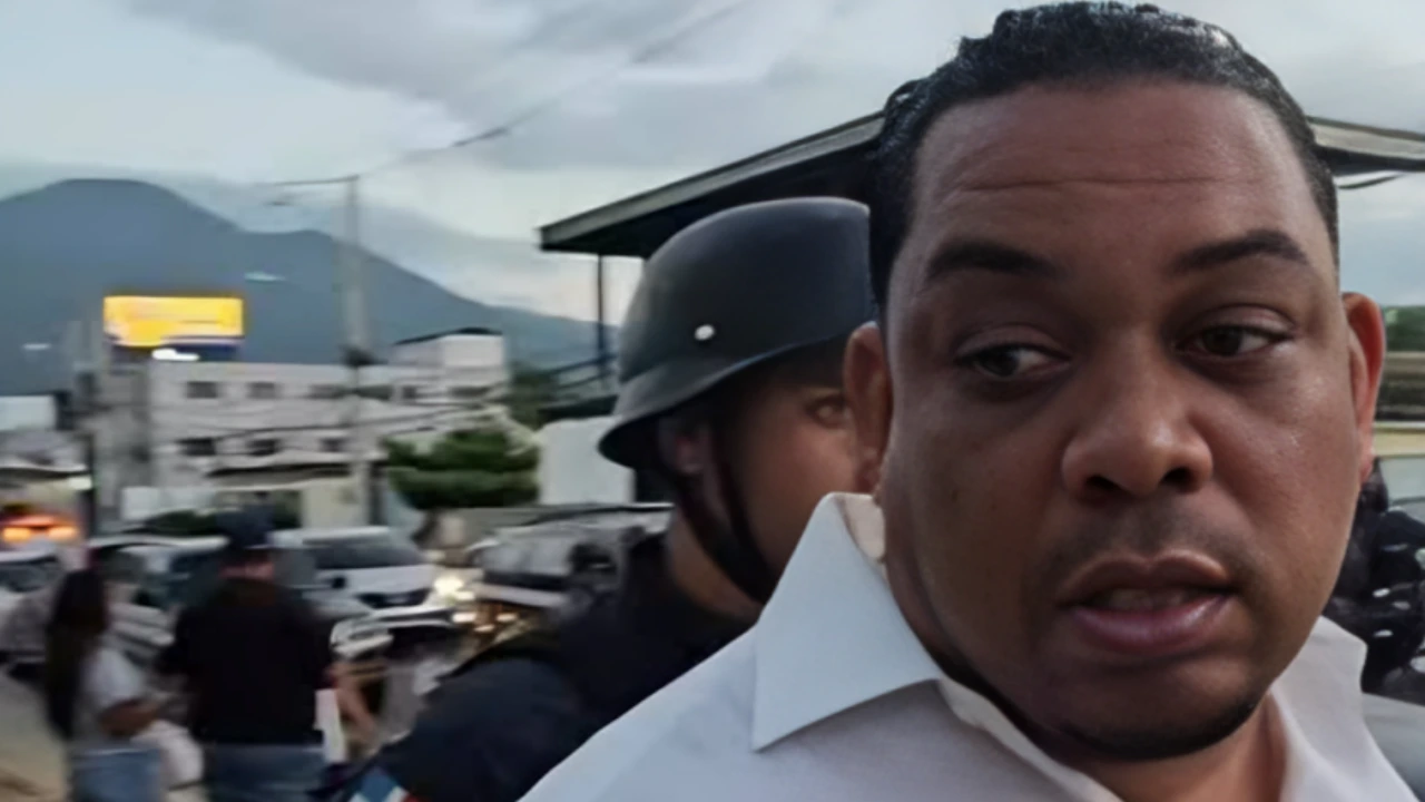 Close-up of a man in a white shirt on a busy street, with a helmeted officer behind him and mountains in the distance.