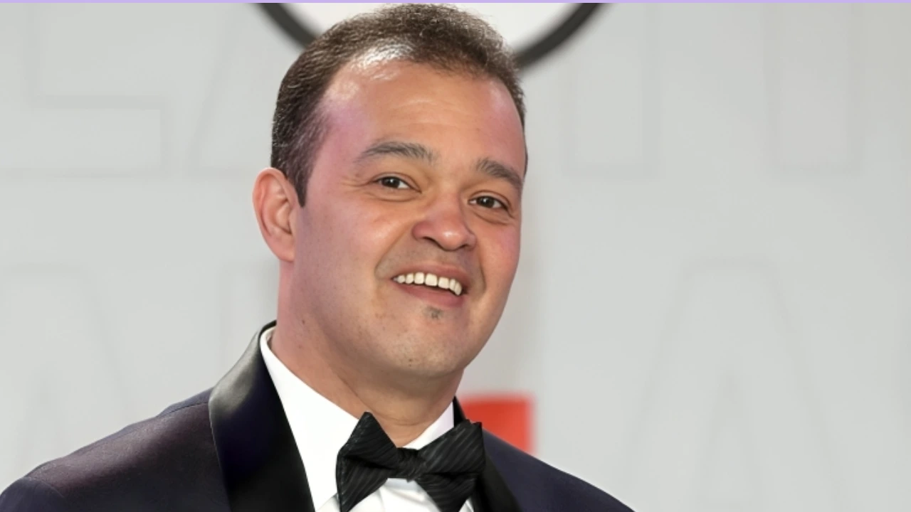 Man in a tuxedo smiling for the camera at a formal event.