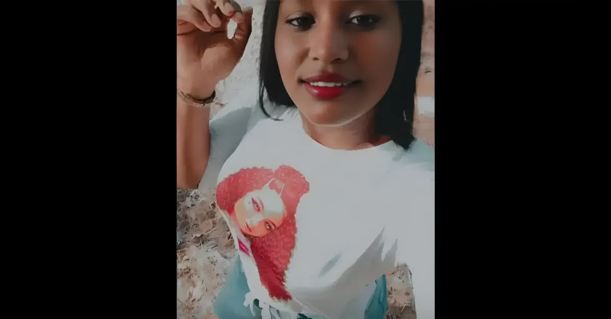 Young woman taking a selfie outdoors, wearing a white T-shirt with a red graphic portrait.