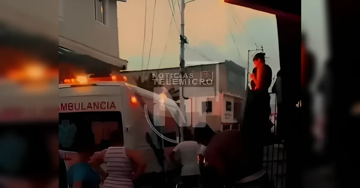 Ambulance with flashing lights on a crowded street as people gather nearby at dusk.