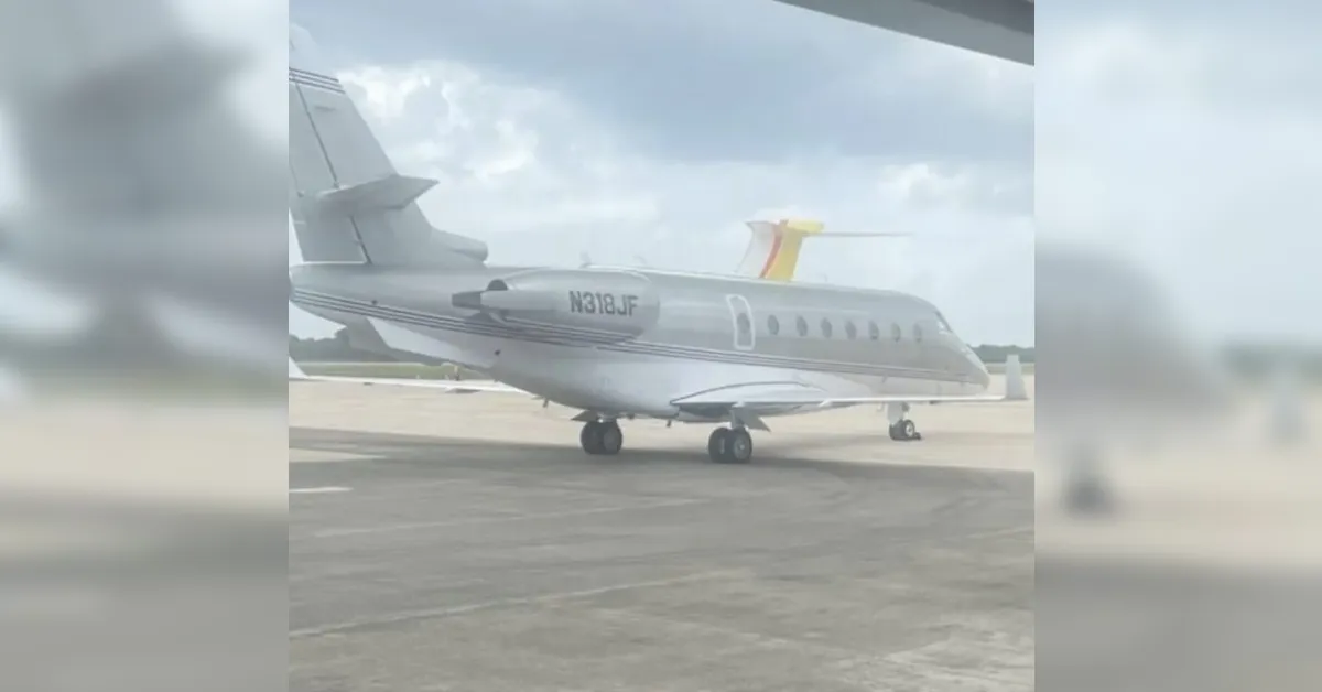 Small private jet parked on a taxiway with tail number N318JF and a silver fuselage.