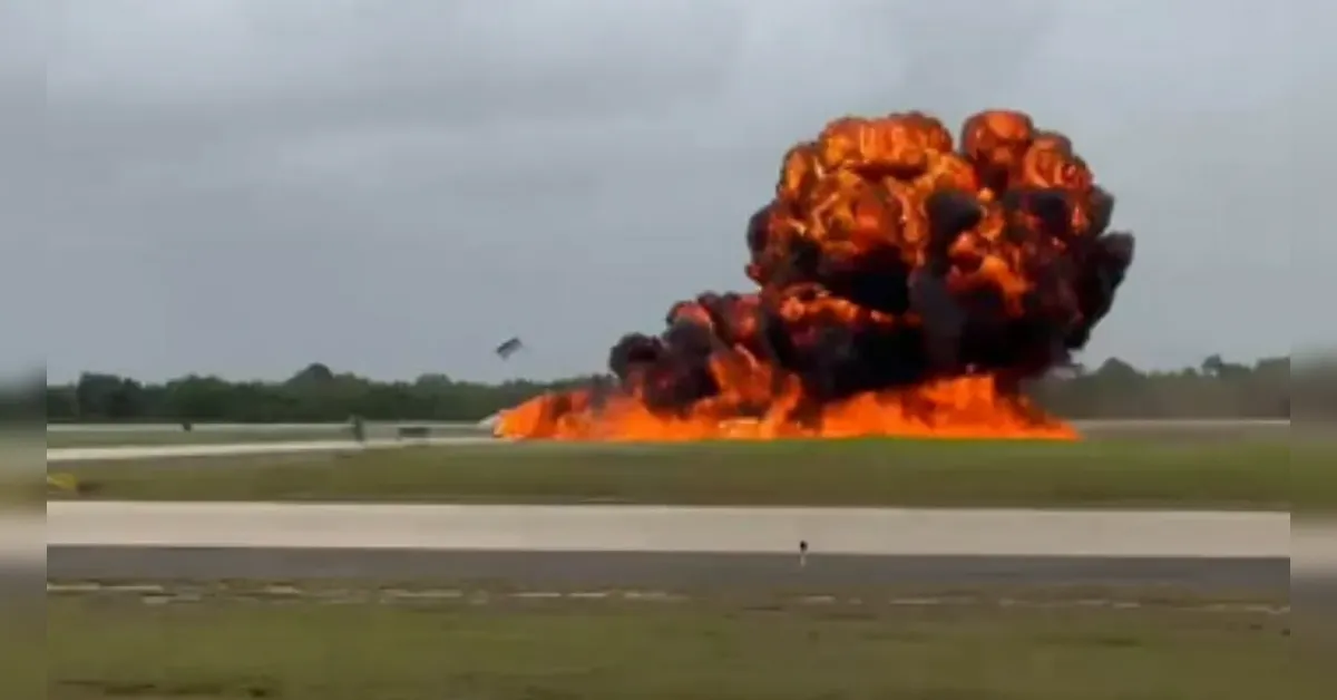 Massive orange-and-black smoke plume rising from a large explosion on a runway at an airfield.