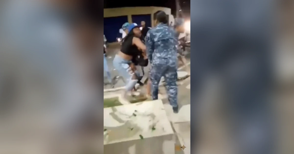 Nighttime street scene of a physical confrontation: a man in a black sleeveless shirt and jeans grappling with someone while a camouflage-uniformed officer watches nearby.