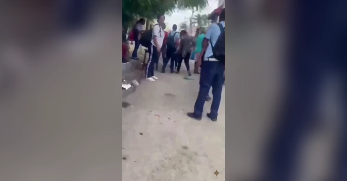 Crowd of people gathered on a dusty street, some wearing backpacks, standing and chatting outdoors near trees and buildings with a few onlookers facing the group to the left.