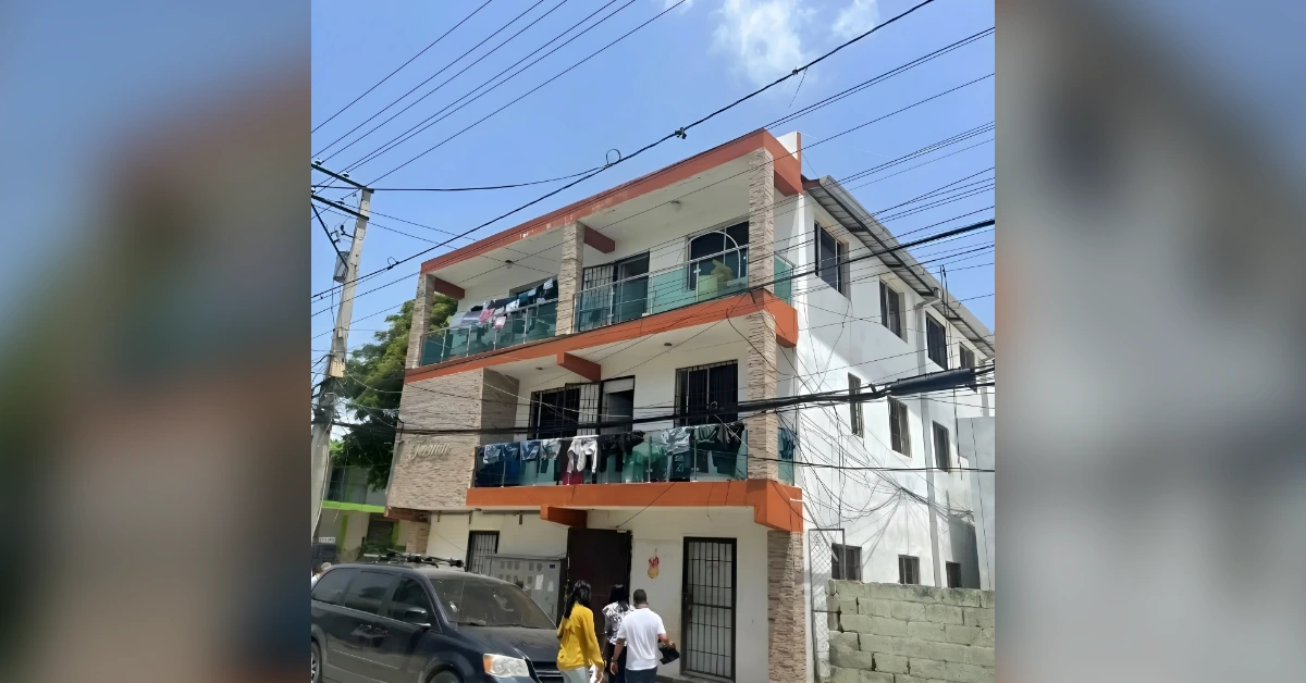 Three-story apartment building with orange trim, balconies with laundry, power lines across the scene
