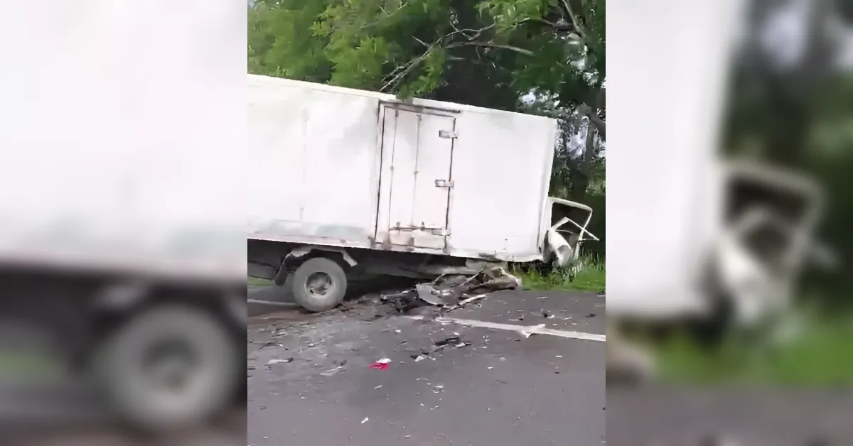 White box truck crashed on a road, front cab crushed and debris scattered on the asphalt.
