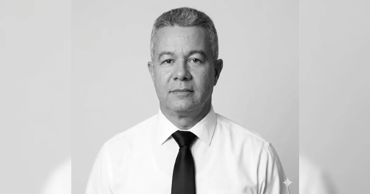 Professional headshot of a middle-aged man in a white shirt and black tie, looking at the camera.
