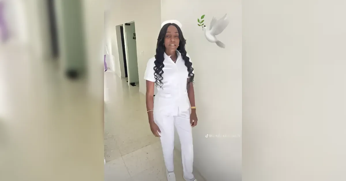 Young woman in a white nursing uniform standing in a bright hospital corridor, ready to assist patients.
