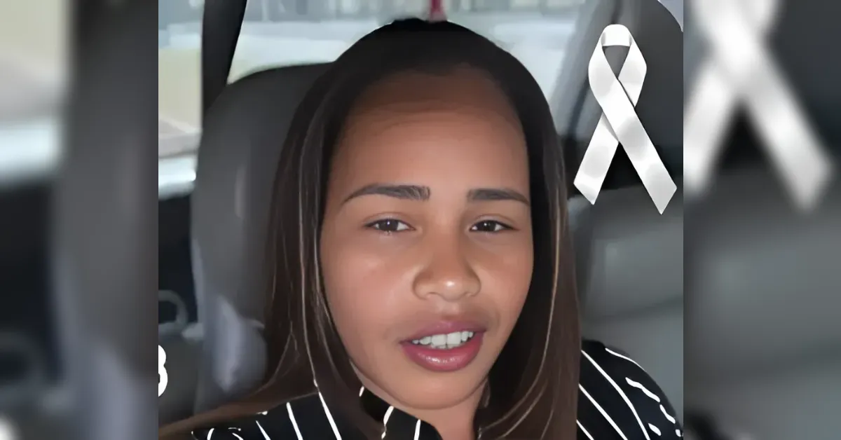 Close-up of a young woman talking to the camera inside a car, with a white awareness ribbon graphic in the corner to symbolize support or remembrance.