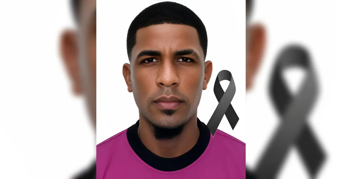 Portrait of a man with short hair wearing a pink shirt, a gray awareness ribbon on his chest, white background.