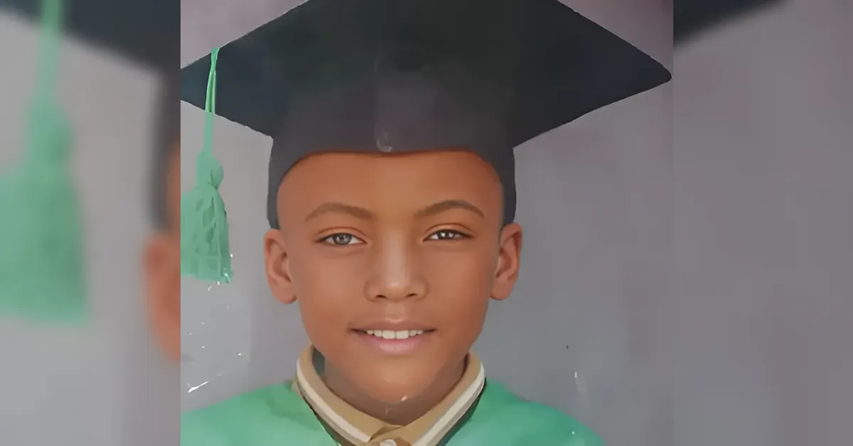 Young student in a green graduation gown and cap, smiling for the camera on graduation day.