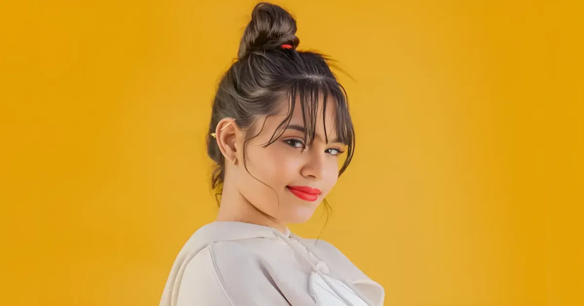 Portrait of a smiling young woman with a top bun against a yellow background on a fashion shootside.