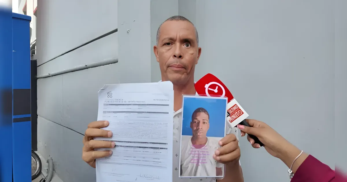 Man shows official documents and a photo ID to the camera during a news interview, microphone near him.