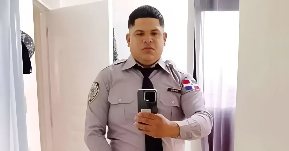Male security guard in a light gray uniform taking a mirror selfie with a smartphone