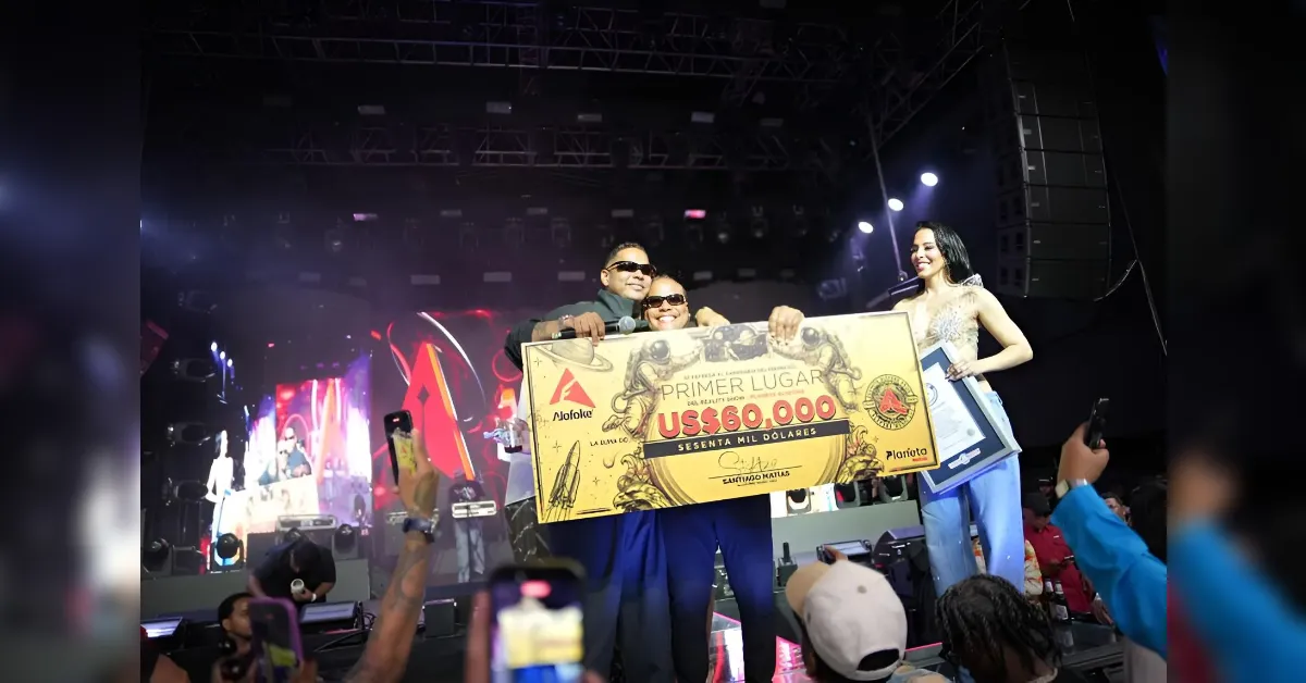 Group of three on stage holding a giant US$60,000 prize cheque, smiling at the audience.