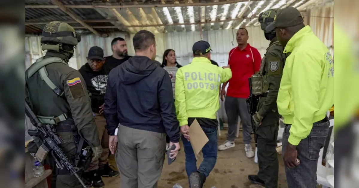 Group of armed officers and civilians inside a makeshift shelter, a uniformed officer points during a briefing.