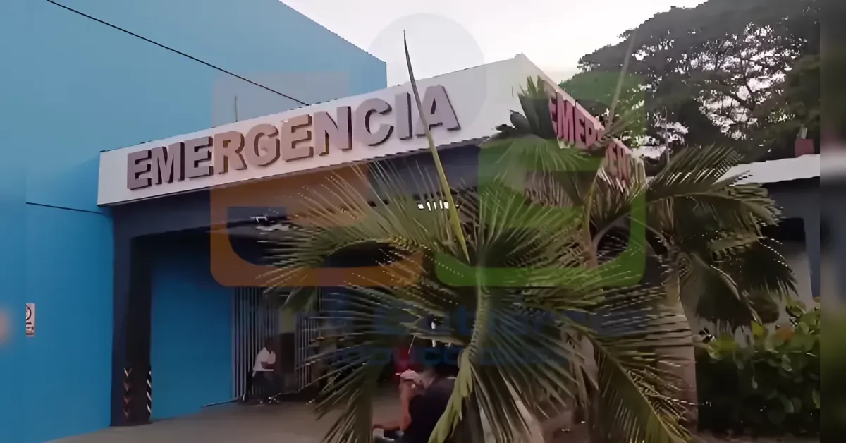 Blue hospital entrance with a large EMERGENCIA sign and a palm tree in front.