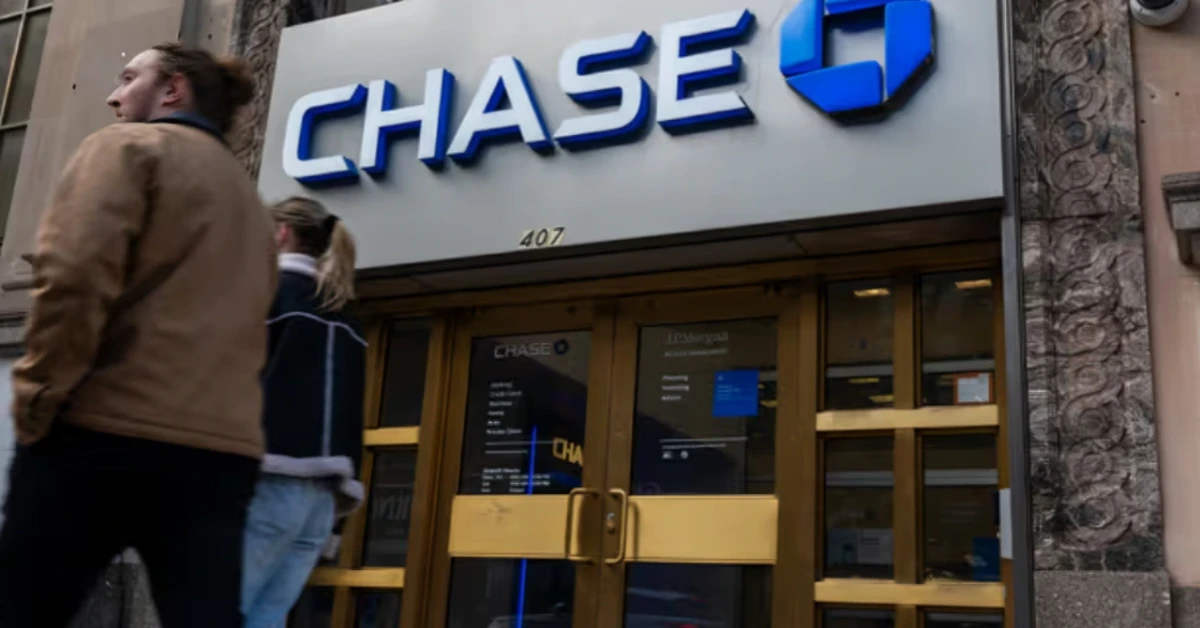 Chase bank storefront with the blue logo and glass double doors; pedestrians walk past on a city street.