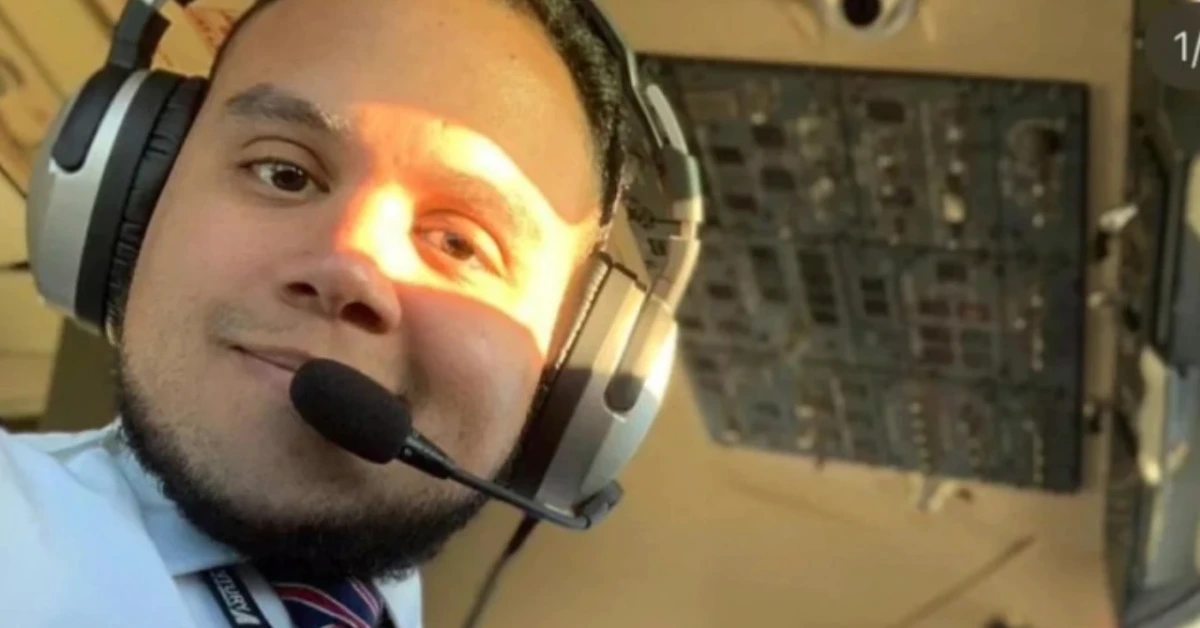 Portrait of a pilot wearing a headset with microphone in a cockpit, smiling at the camera
