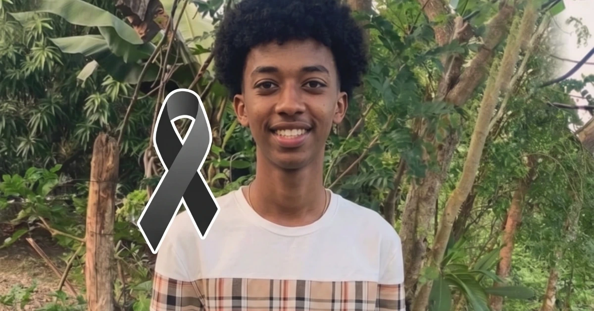 Smiling young man standing outdoors in a green garden with a large black mourning ribbon graphic over his torso, conveying a memorial tribute.