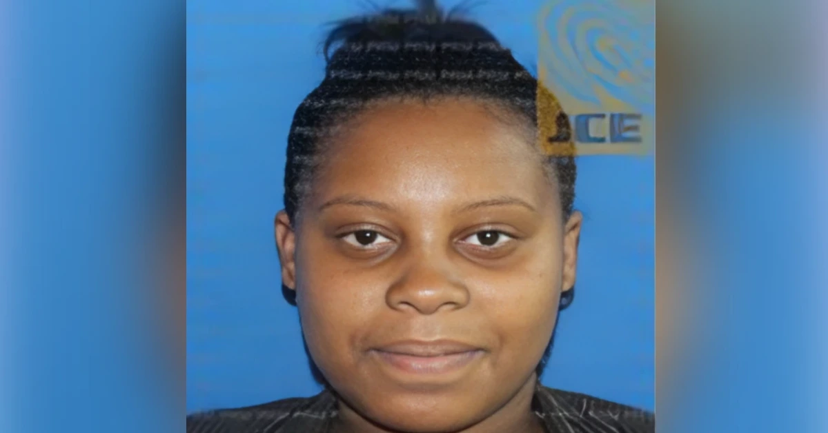 Portrait of a young woman with braided hair against a blue backdrop, neutral expression.