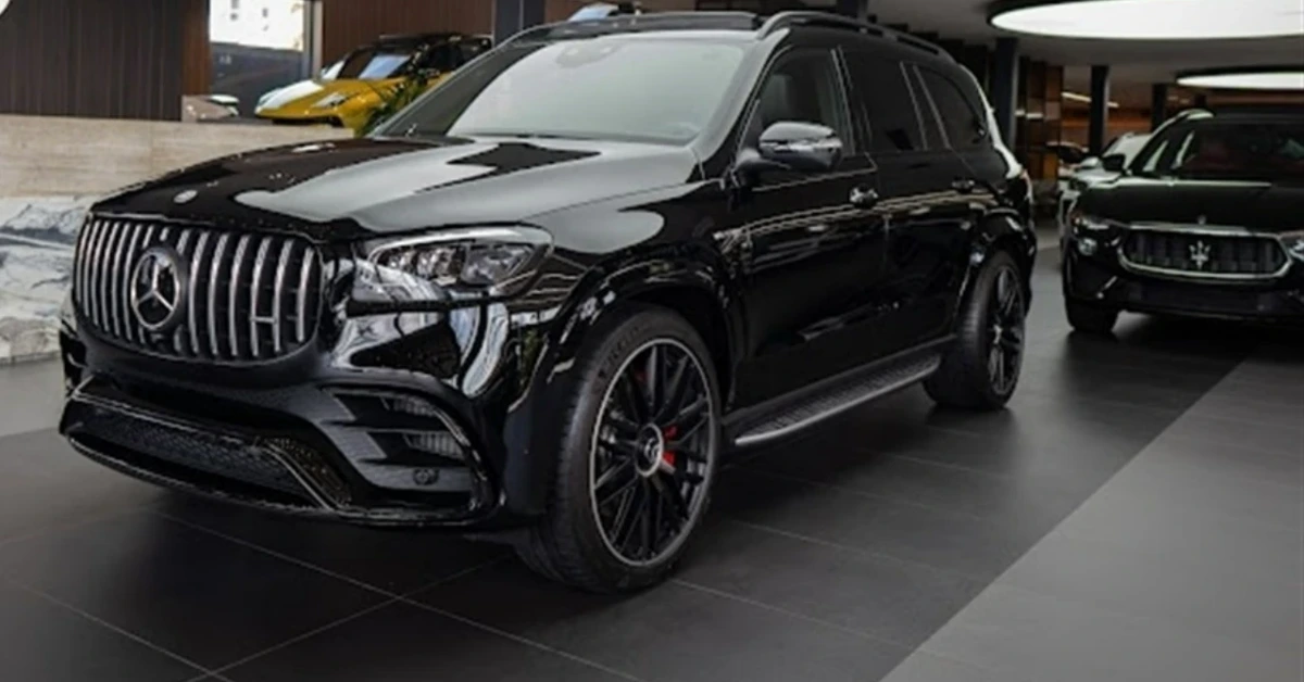 Black Mercedes-Benz SUV on display in a car showroom, with a Maserati visible in the background.