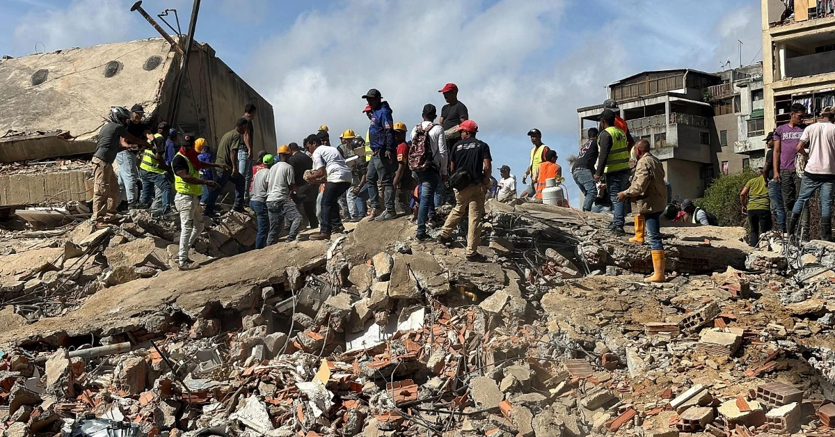 Group of rescuers and volunteers standing on rubble and a collapsed building after a disaster