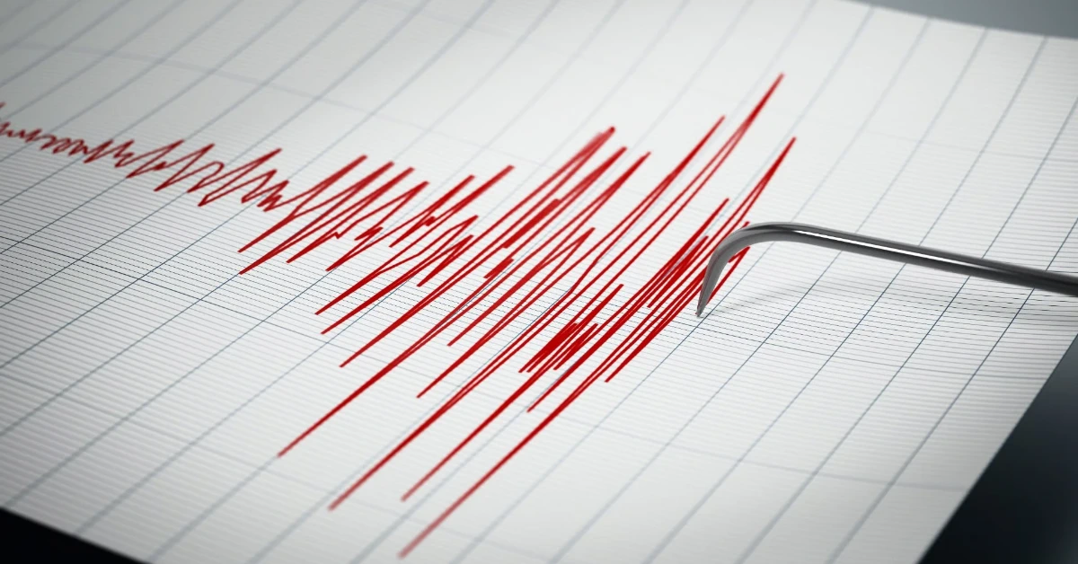 ECG printout with a jagged red heartbeat waveform and a curved metal medical instrument resting on the paper