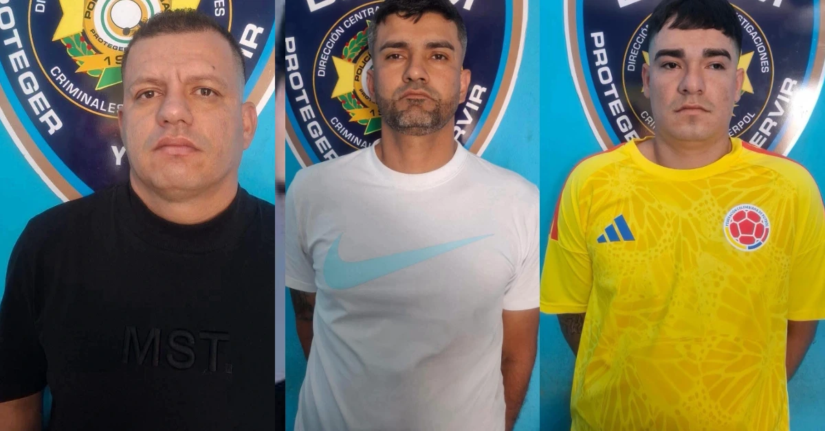 Three men pose side by side in front of a circular police emblem; left man in black, middle man in white with a light blue logo, right man in yellow Colombia soccer jersey.