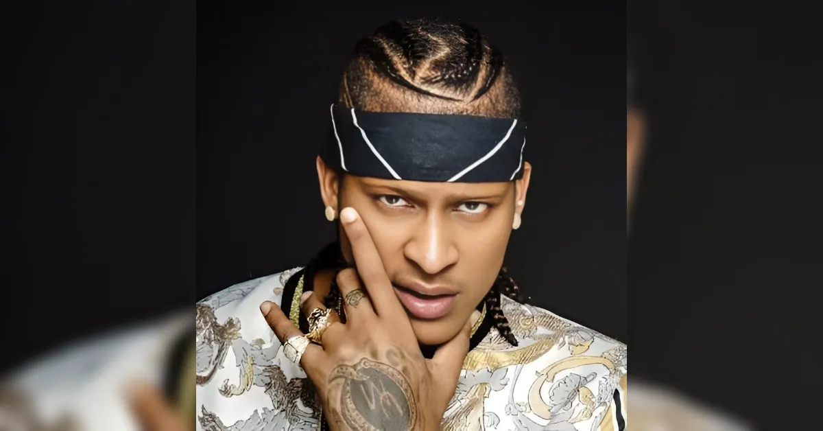 Close-up of a person with a black bandana, intense gaze, finger touching the face, wearing a patterned shirt.