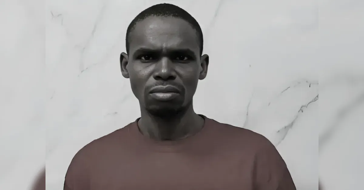 Man with a serious expression facing the camera, wearing a brown shirt against a light marble background