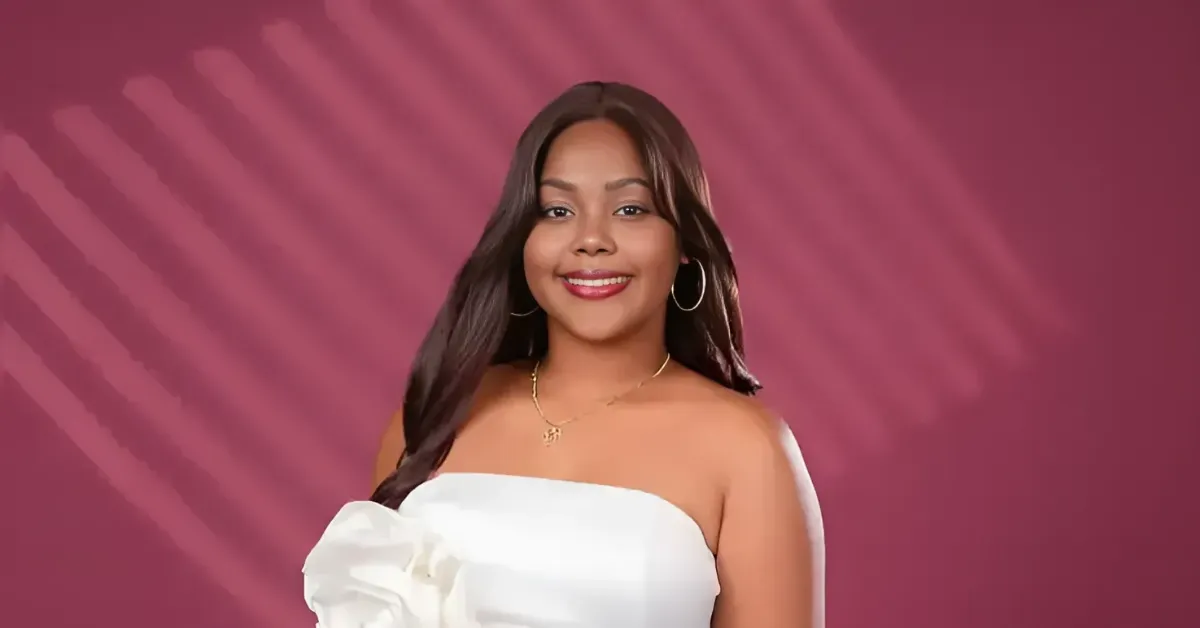 Portrait of a smiling woman with long dark hair, wearing a white off-the-shoulder top against a pink background with diagonal patterns.
