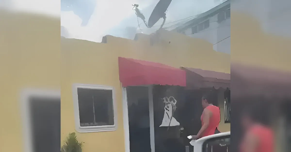 Yellow storefront with a pink awning; a man in a red sleeveless shirt stands outside near the glass door.