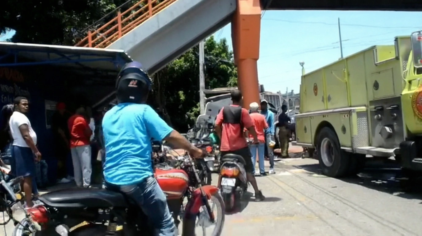Crowd gathered on a street beside a yellow fire truck; motorcycles parked in the foreground.