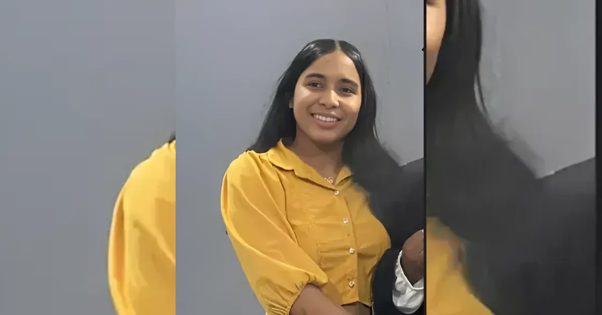 Smiling woman with long dark hair in a yellow blouse poses for a photo against a neutral background.