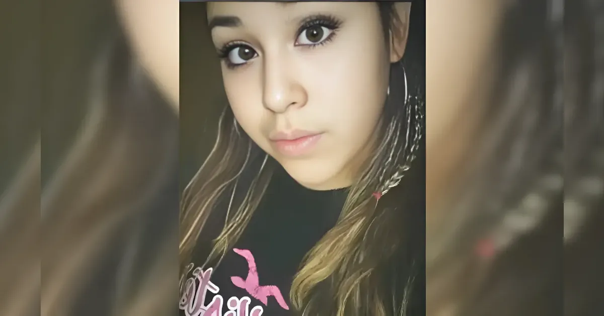 Close-up portrait of a young woman with long wavy hair and hoop earrings, looking at the camera.