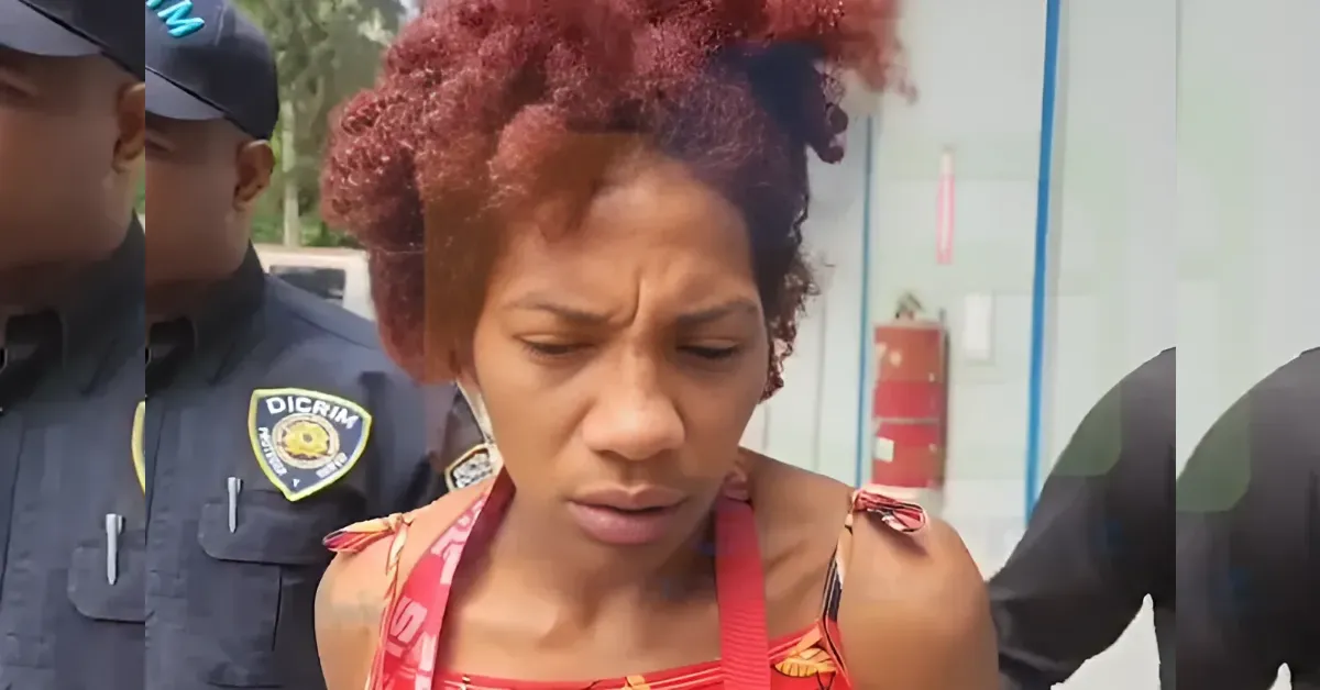 Distressed woman with red hair being escorted by two uniformed officers outside a building.