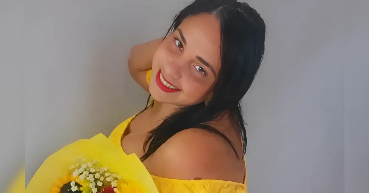 Smiling woman in a yellow off-shoulder dress holding a bouquet of sunflowers against a gray background.