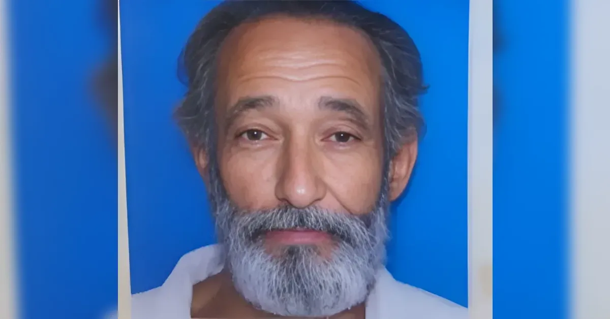 Close-up portrait of a middle-aged man with a gray beard against a blue background, looking at the camera.