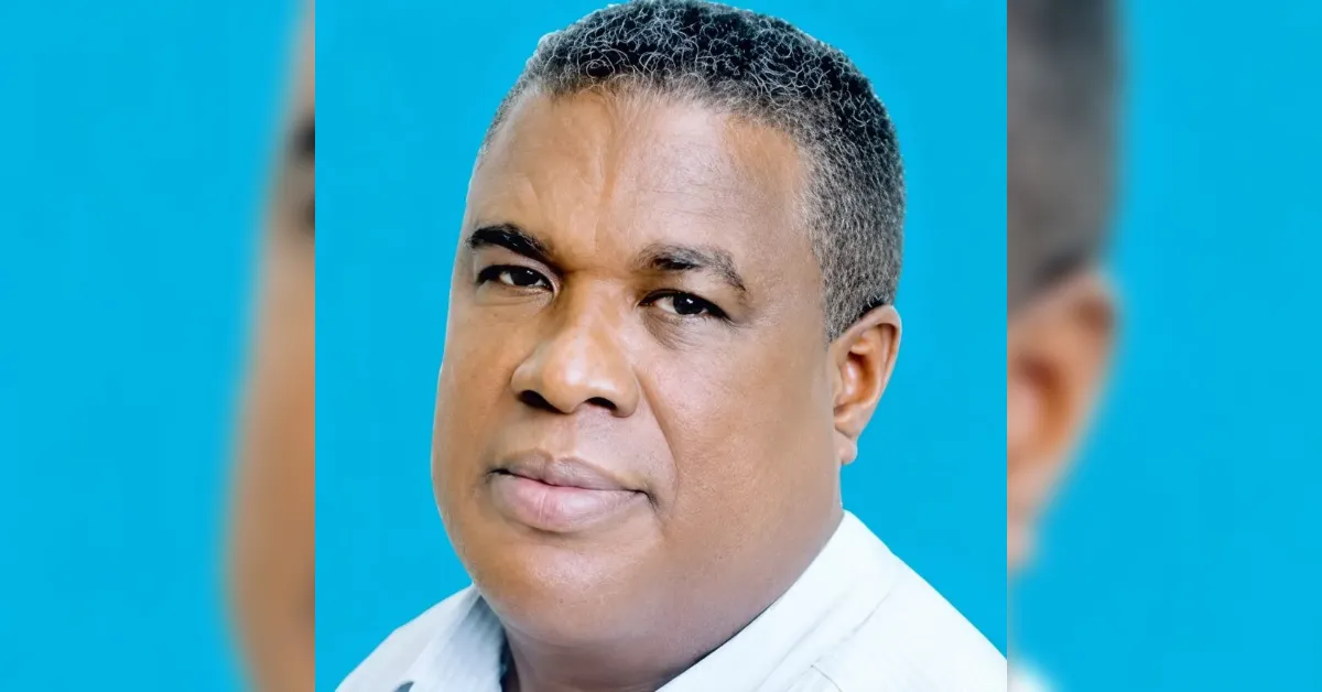 Portrait of a middle-aged man with short, graying hair against a bright blue backdrop, looking straight at the camera.