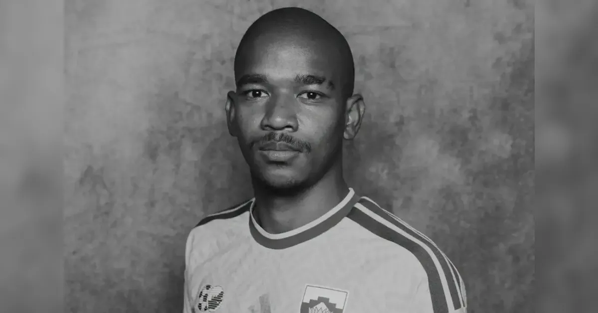 Portrait of a man wearing a light sports jersey against a textured gray wall.
