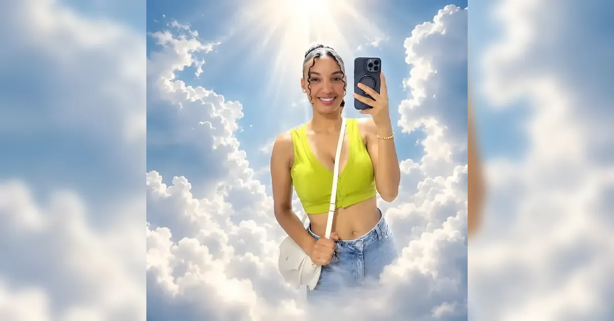 Selfie of a smiling woman in a lime green sleeveless top and jeans, holding a white bag, against a bright blue sky with fluffy clouds.