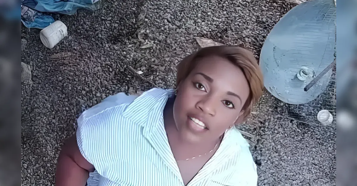 Woman lying on rocky ground outdoors, looking up at the camera, wearing a light blue striped shirt.