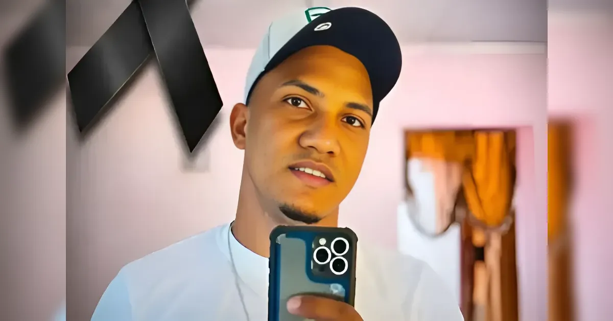 Young man taking a selfie in a mirror, holding a phone with a triple-camera setup under a cap.