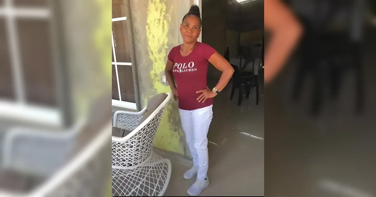 Woman standing outdoors with hands on hips beside a chair, wearing a maroon Polo Ralph Lauren shirt and white pants with light sneakers.