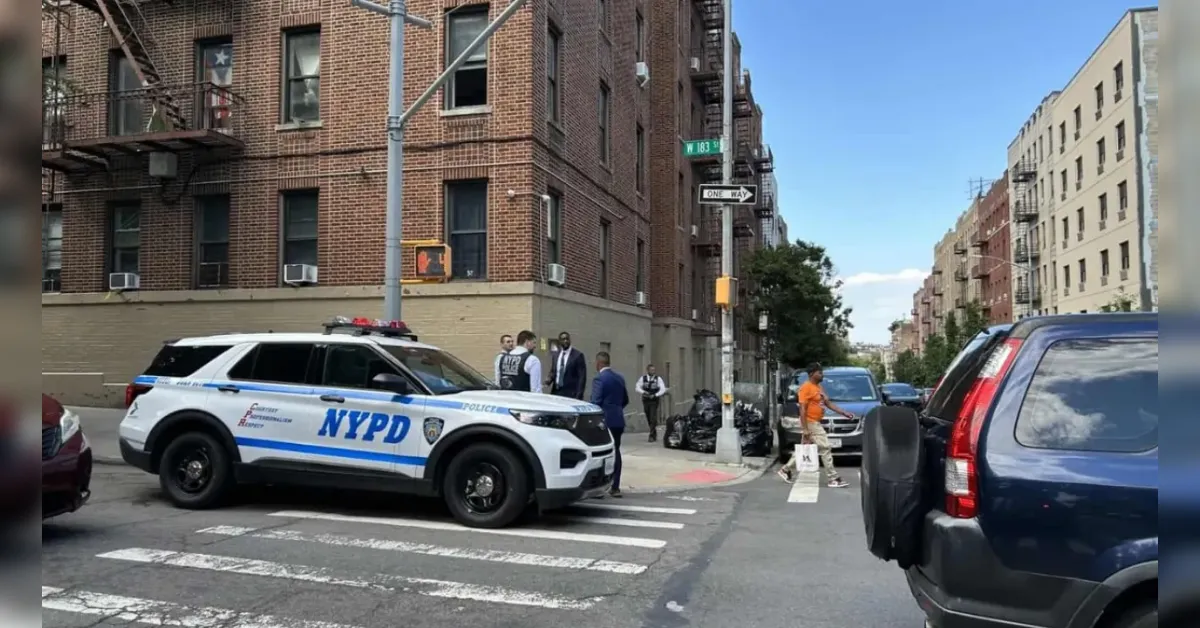 NYPD police SUV blocking a crosswalk at a city intersection with pedestrians nearby and brick buildings.