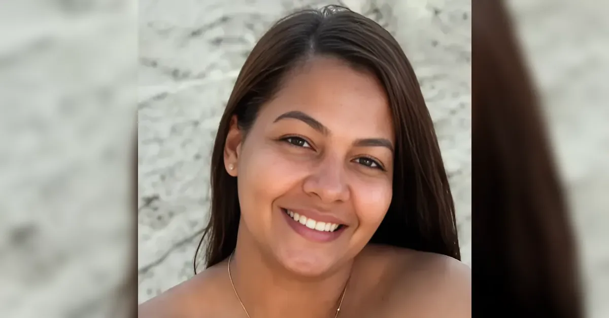 Smiling woman with long dark hair facing the camera, marble-textured background behind her.
