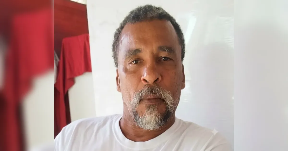 Portrait of a middle-aged man with a gray goatee and mustache wearing a white T-shirt, facing the camera.