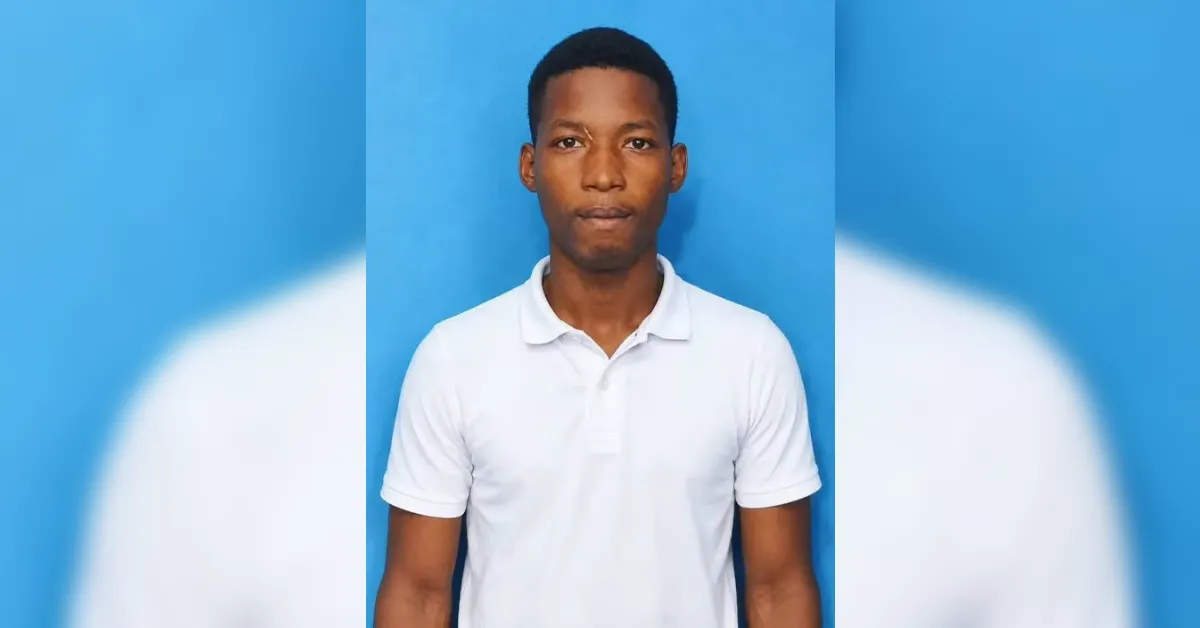 Young man in a white polo shirt standing against a blue backdrop.